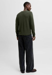 Cămașă verde măsliniu cu mâneci lungi, cu tivuri ajustate, asortată cu blugi negri din denim largi. Material texturat și siluetă relaxată.