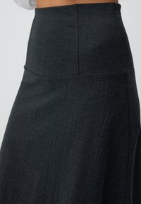 Zwarte kokerrok gemaakt van textiel met structuur. Hoge tailleband, gladde afwerking en een getailleerd silhouet dat naar de zoom toe toelopend is.