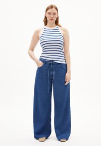 Gestreept mouwloos shirt in wit en blauw, gecombineerd met losse, hooggetailleerde blauwe denim broek met een drawstring taille.