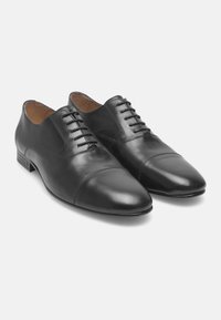 Schwarze Lederschuhe mit glatter Oberfläche, runder Spitze, Schnürverschluss und subtilen Kappenverzierungen. Niedriger Absatz und schlanke Silhouette.