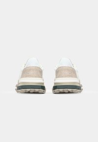 Sportschoenen met een beige en witte suede bovenwerk, textuur hiel, dikke witte tussenzool en rubberen buitenzool met opvallende profielpatronen.