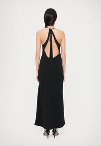 Μαύρο μάξι φόρεμα με λαιμόκοψη halter και ανοιχτή πλάτη. Διαθέτει απαλό ύφασμα, εφαρμοστό μπούστο και ρέον φούστα.