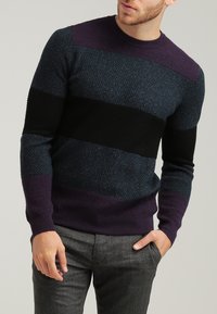 Sweter dzianinowy z teksturowanym wzorem i poziomymi paskami w ciemnym niebieskim, czarnym i purpurowym kolorze. Okrągły dekolt i ściągacze przy mankietach.