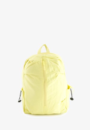 Gul stofrygsæk med frontlomme med lodret lynlås og sidejusterbare snorede rum.