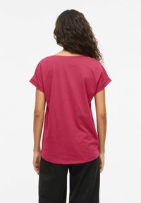 Κοντομάνικη, άνετη μπλούζα σε σκούρο ροζ βαμβάκι, με στρογγυλή λαιμόκοψη και καμπυλωτό τελείωμα στο πίσω μέρος.