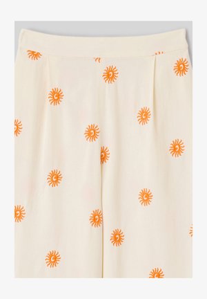 Tissu couleur crème avec des motifs brodés en forme de soleil orange espacés de manière régulière, montrant une ceinture et un détail plissé.