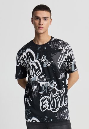 Maglietta nera con stampa in stile graffiti in bianco e grigio. Maniche corte, collo rotondo e vestibilità comoda con vari disegni di testo.