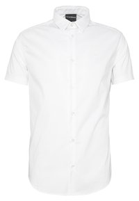 Vit kortärmad skjorta med knäppning och spetsig krage, med en subtil emblem på bröstet och en mjuk tygtextur.