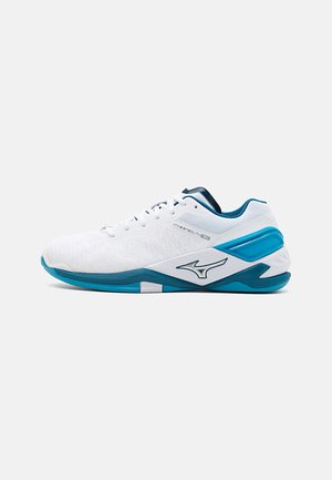 Baskets blanches avec un upper texturé, des accents bleus et verts, et un logo distinctif. Présentent un profil bas et une semelle rembourrée.