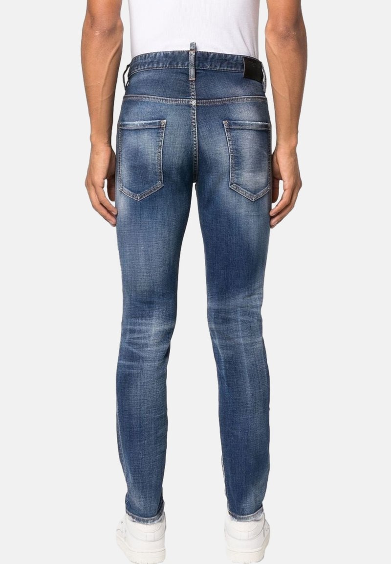 Jeans de denim azul ajustados con un acabado desgastado, que cuentan con cinco bolsillos y una etiqueta negra en la cintura. Con un corte de pierna estrecha.