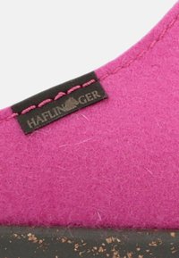 Roze vilten slof met een gestructureerd oppervlak, kurken zool en een zwart label dat op de zijkant is gestikt met de tekst "Haflinger."