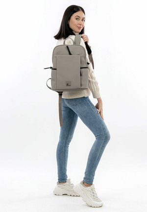 Hall hall kangaskott ees tasku, mustad detailid ja reguleeritavad rihmad. Modell kannab helekollast kampsunit ja siniseid pükse, seisab külje peal.