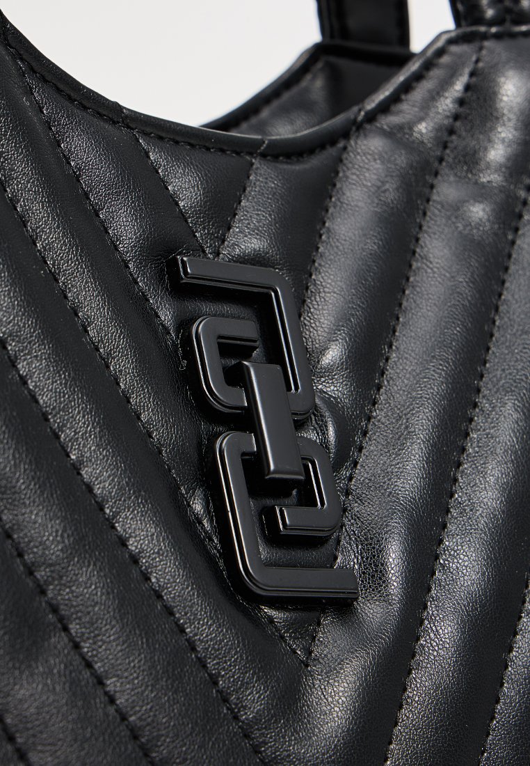 Sac à main en cuir noir avec un motif matelassé, présentant un détail de boucle géométrique noire brillante à l'avant, accentué par une texture lisse.