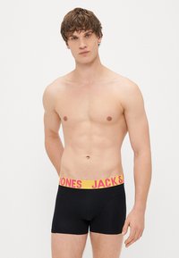 Černé boxerky s širokým elastickým pasem, na kterém je výrazný nápis "JACK & JONES" ve žluté a růžové barvě. Hladký materiál s přiléhavým střihem.