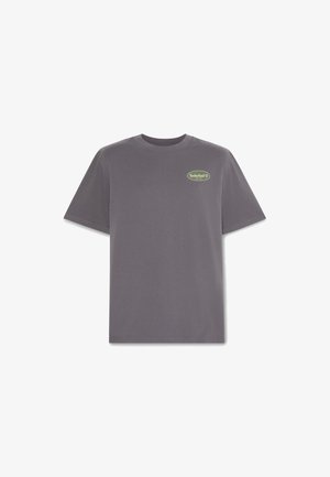 Graues Baumwoll-T-Shirt mit kurzen Ärmeln, Rundhalsausschnitt und einem kleinen grünen Timberland-Logo auf der linken Brust. Standardpassform und glatte Textur.