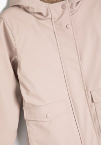 Lyserød vandafvisende jakke med hætte, trykknaplukninger, to frontlommer og glat tekstur. Simpelt design med rene linjer.