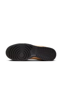 Semelle extérieure noire en caoutchouc d'une basket avec des motifs de traction circulaires et en grille, affichant la marque Nike près de la zone de la voûte plantaire.