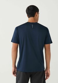 Mørkeblå trænings t-shirt med korte ærmer og rund halsudskæring. Har et reflekterende accent på ryggen. Glat, let stof.