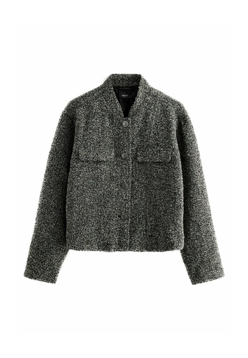 Harmaa ja musta houndstooth-kuvioinen takki, lyhyt malli, jossa on seisova kaulus, kaksi rintataskua ja etunapitus.