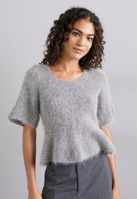 Απαλή γκρίζα χαμηλή μπλούζα κοντά μανίκια φτιαγμένη από μαλακό, χνουδωτό υλικό με στρογγυλή λαιμόκοψη και στρωμένη ρίγα, δημιουργώντας μια υφή.