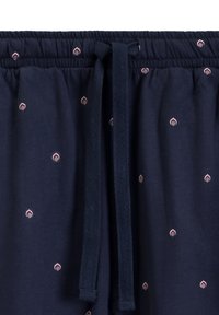 Granatowe spodnie dresowe z elastycznym pasem, sznureczkiem oraz małymi, diamentowymi różowymi wzorami na całej powierzchni. Miękka tekstura materiału.