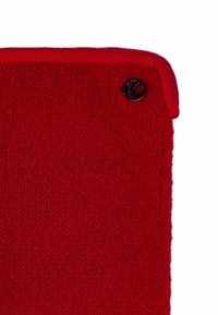 Red knitted fabric with a smooth texture, featuring a folded top and a black logo accent on the side.