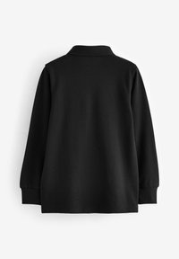 Polo a maniche lunghe nera con una texture morbida, dotata di colletto e polsini a coste, progettata senza loghi o motivi visibili.