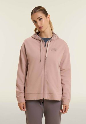 Felpa con zip di colore rosa chiaro realizzata in tessuto morbido, con fodera del cappuccio a fantasia, due tasche frontali e dettagli con cordoncino.