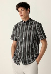 Cămașă cu mânecă scurtă, de culoare neagră �și gri, cu un model de dungi verticale și motive cu frunze. Guler mandarin și design cu nasturi la față.