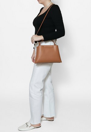 Sac à main en cuir marron de forme trapézoïdale, avec un design structuré, une poignée supérieure et des accents en métal argenté.