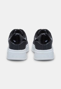 Musthave musta läikiv nahk sneakers, millel on tekstuuriga valge tallaga, pehmendatud krae ja sujuvad jooned, sobivad erinevateks vabaaja tegevusteks.