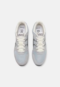 Baskets grises et bleu clair en matériaux en daim et en maille, avec des lacets blancs, un logo sur la languette et trois rayures sombres sur le côté.