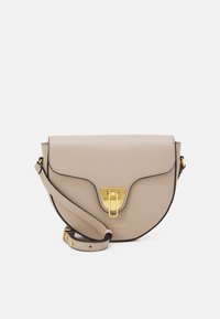 Borsa a tracolla in pelle beige con silhouette curva, accessori in oro, chiusura a pattina e tracolla removibile. Presenta un logo impresso.
