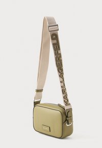 Oliwkowa prostokątna torba na ramię z szerokim beżowym paskiem, wyszywana napisem "KARL LAGERFELD" oliwkowymi literami.