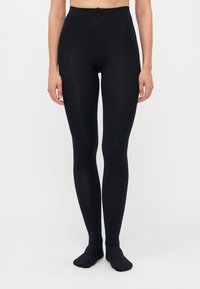 Sorte leggings med høj talje, glat tekstur og tætsiddende pasform. Har et subtilt mønster og går ned til en fodet ankeldesign.