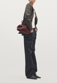Gray blazer, white top, dark blue wide-leg jeans, black pointed-toe shoes, and a woven burgundy handbag. Smooth textures with contrasting details.