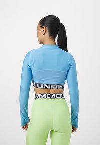 Heledad siniste crop top helesinises ribberdatud osaga. Must bränditud vöökoht. Ühildatud kõrge vöökoha, erksate roheliste legginsitega.
