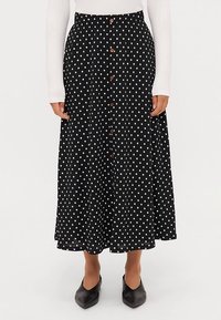 Melnas midi svārki ar baltām polka punktiem, ar pogu aizdari priekšpusē un izplatītu dizainu. Izgatavoti no viegla auduma.