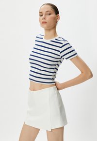 Randig kort topp i vitt och marinblått, ribbat tyg, rund halsringning; ihop med en vit minikjol med sidogylf.