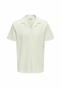 Kortärmad polo i ljusbeige, texturerat tyg, med en klädd krage och rak fåll för en avslappnad passform.