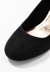 Scarpa flat in suede nero con punta arrotondata e lati bassi, presenta una soletta in pelle liscia e dettagli di cucitura discreti.