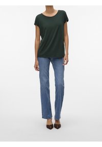 Ciemnozielona koszulka z krótkim rękawem o luźnym kroju, zestawiona z jasnoniebieskimi dżinsami prostymi i brązowymi szpilkami w szpic.