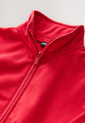 Punainen fleece-takki korkealla kauluksella ja vetoketjulla. Sileä pinta, jossa ompelu yksityiskohtia ja sisäpuolella kauluksen kohdalla näkyvä etiketti.