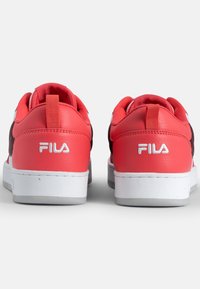 Red and white leather sneakers with a flat white sole, featuring a smooth texture and a logo on the heel. Back view highlights stitching detail.