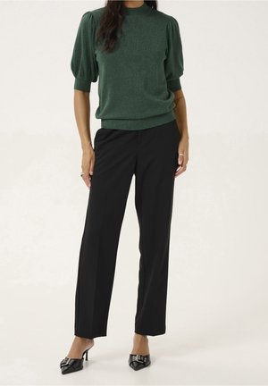 Zelený třpytivý svetr s krátkými nafouknutými rukávy, doplněný černými kalhotami a černými lodičkami s špičatou špičkou. Čistý a upravený vzhled.