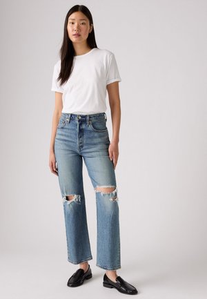 Light blue ripped jeans with a high waist, straight leg cut, and frayed hem, paired with a plain white short-sleeve t-shirt and black loafers.