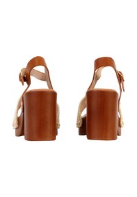 Paire de sandales marron à talons carrés avec brides à la cheville et fermetures à boucle, vue de dos sur un fond blanc.