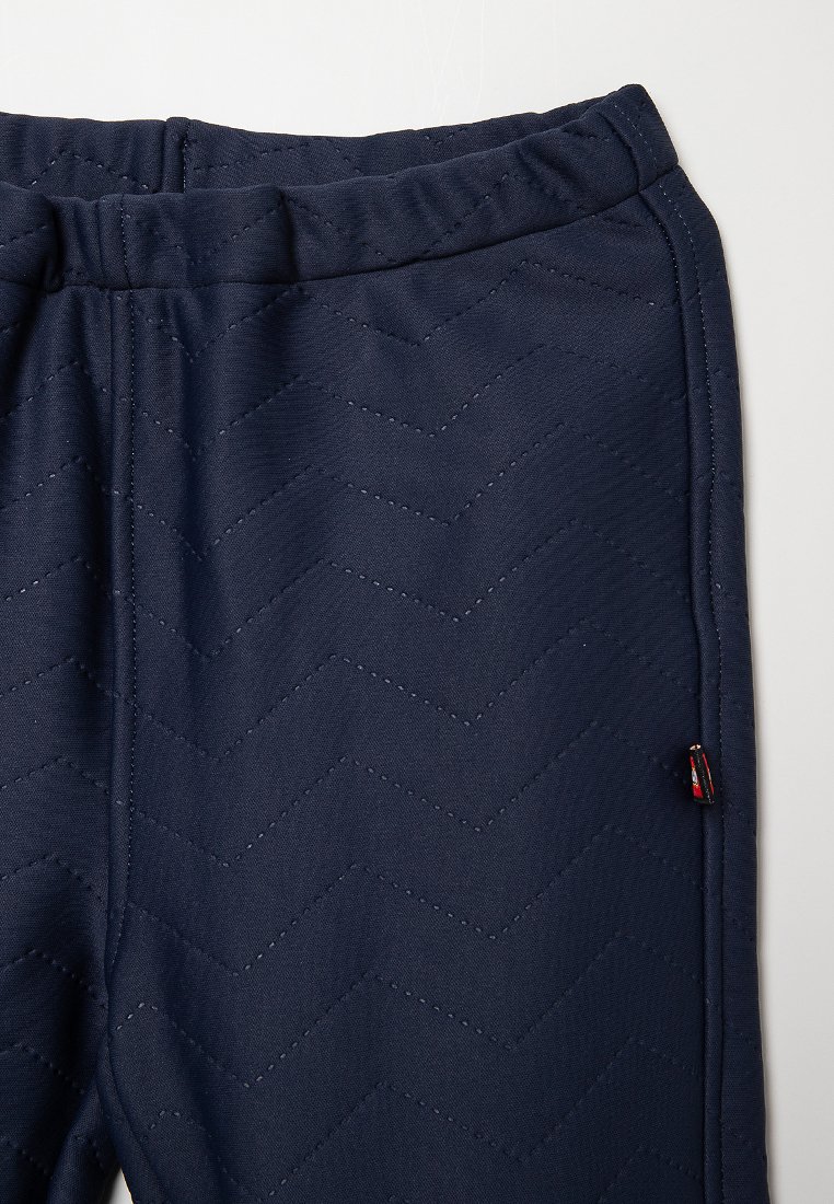 Pantaloni joggers imbottiti color navy con motivo a chevron, vita elasticizzata e un piccolo accento di logo rosso e nero sulla cucitura laterale.