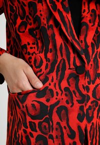 Punamusta leopardi-kuvioitu bleiseri, jossa on käännetty kaulus, yksirivinen nappikiinnitys ja sivutasku, valmistettu sileästä kankaasta.