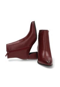 Botines de cuero burdeos con un diseño elegante, punta afilada y cremallera lateral; el tacón bajo tipo bloque proporciona estabilidad y comodidad.